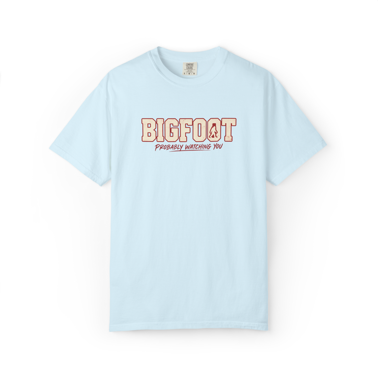 Light blue Bigfoot t shirt with cream varsity-style Bigfoot lettering, small Sasquatch silhouette, and Probably Watching You text