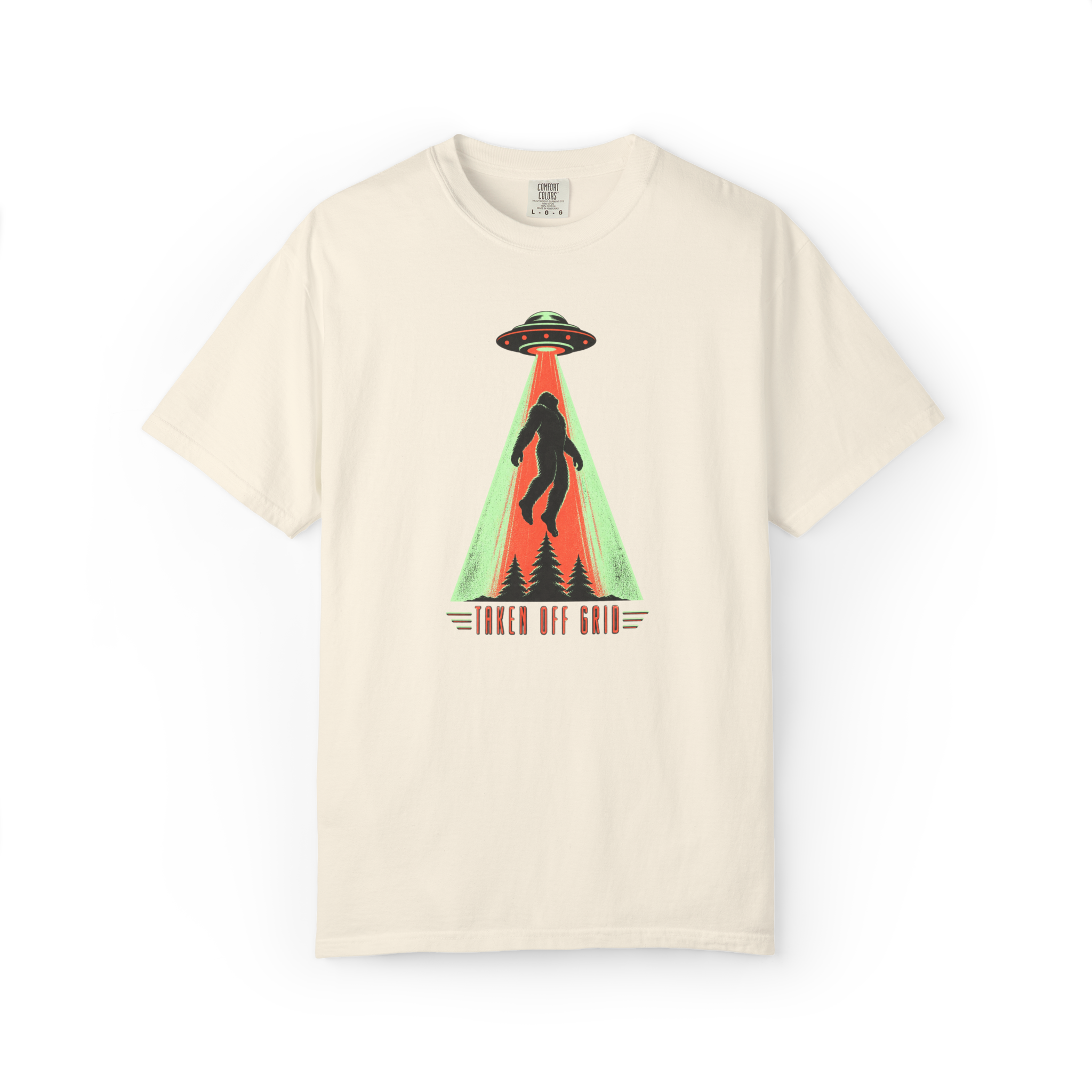 Taken Off Grid Bigfoot shirt featuring a Sasquatch being abducted by a UFO above pine trees with retro text on a cream tee