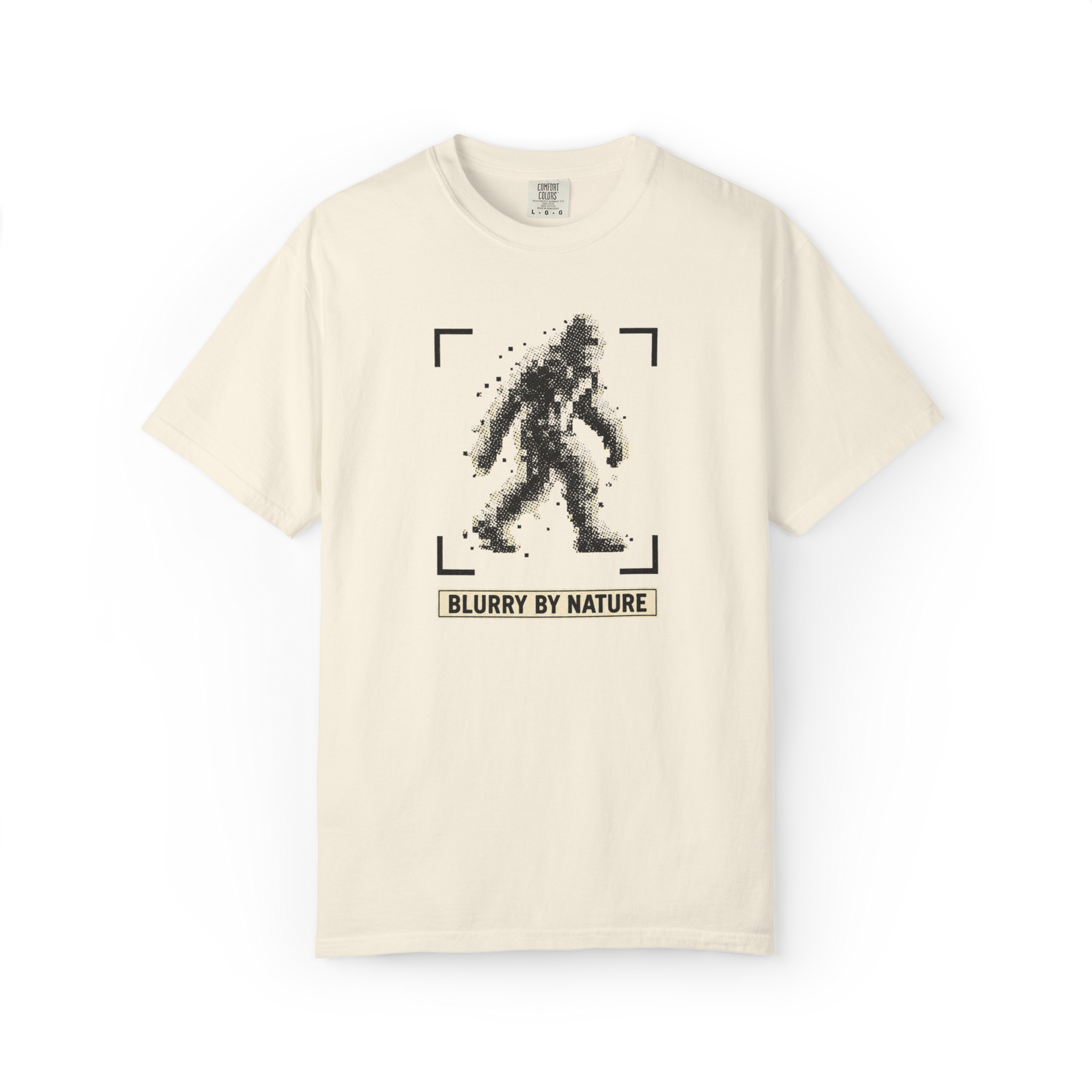Ivory Bigfoot t shirt featuring a pixelated blurry Sasquatch inside camera focus brackets with Blurry By Nature text