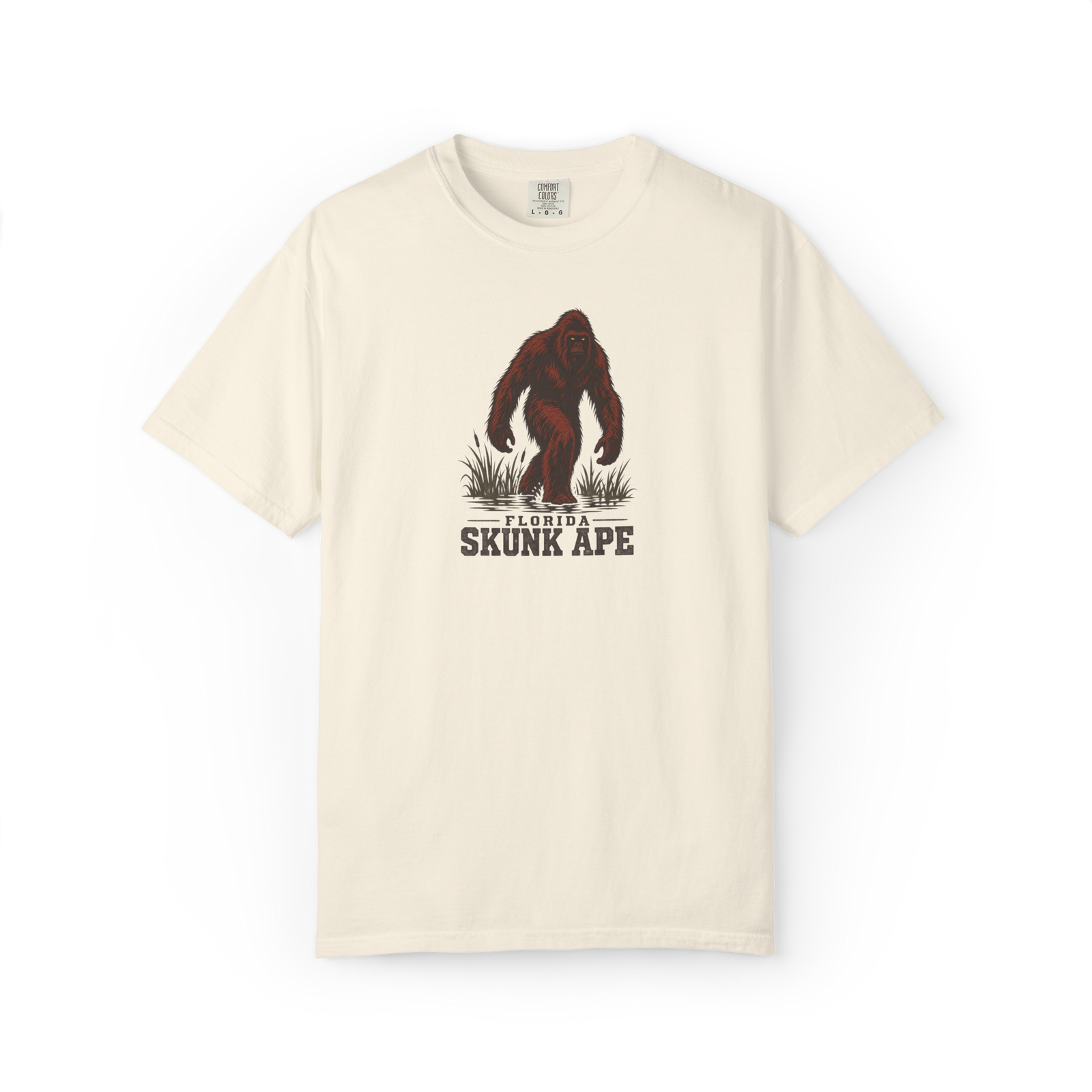 Ivory Florida Skunk Ape t shirt with a full-body dark red-brown skunk ape walking through swamp grass above Florida Skunk Ape text