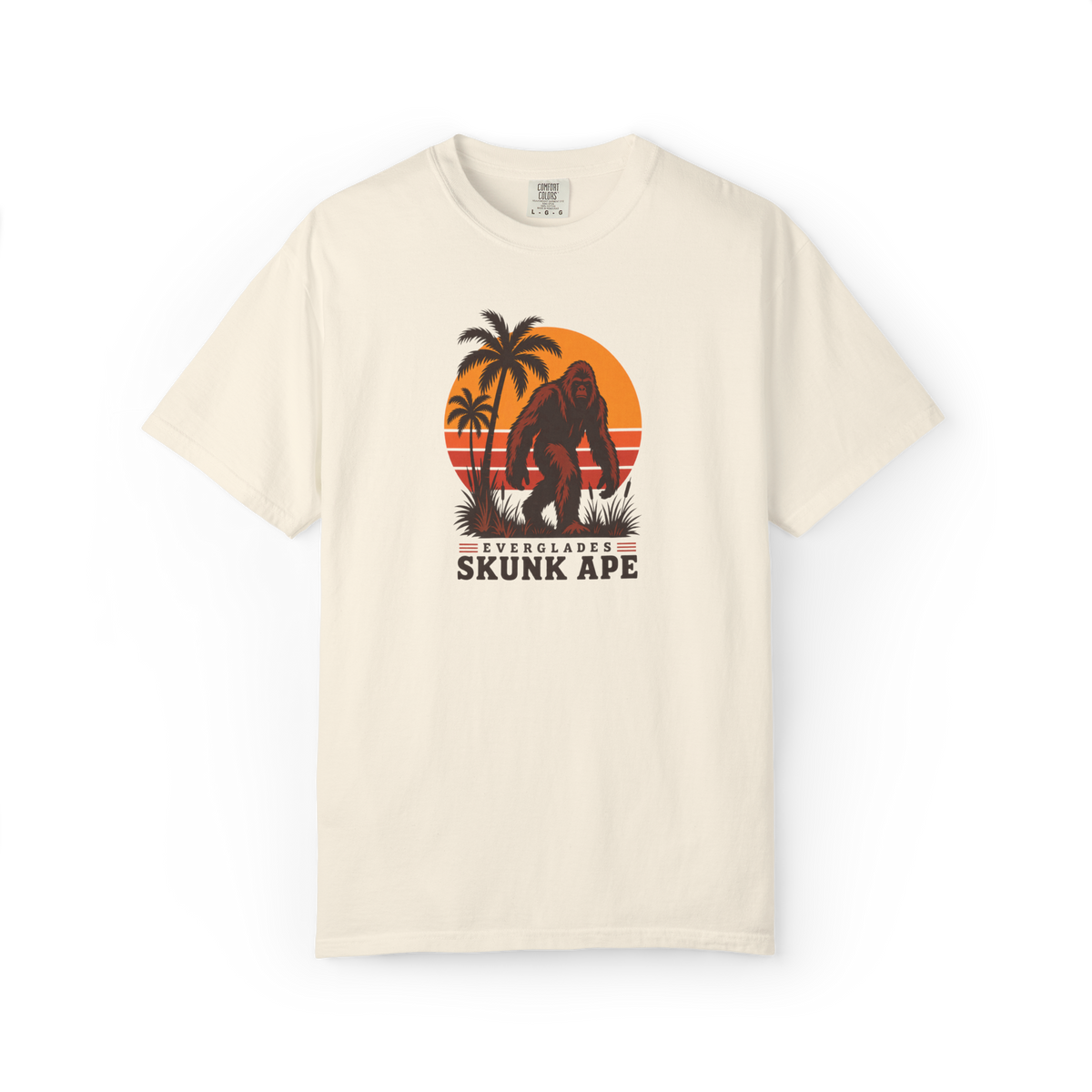 Ivory Everglades Skunk Ape t shirt with a full-body red-brown skunk ape, palm trees, sunset stripes, and Everglades Skunk Ape text