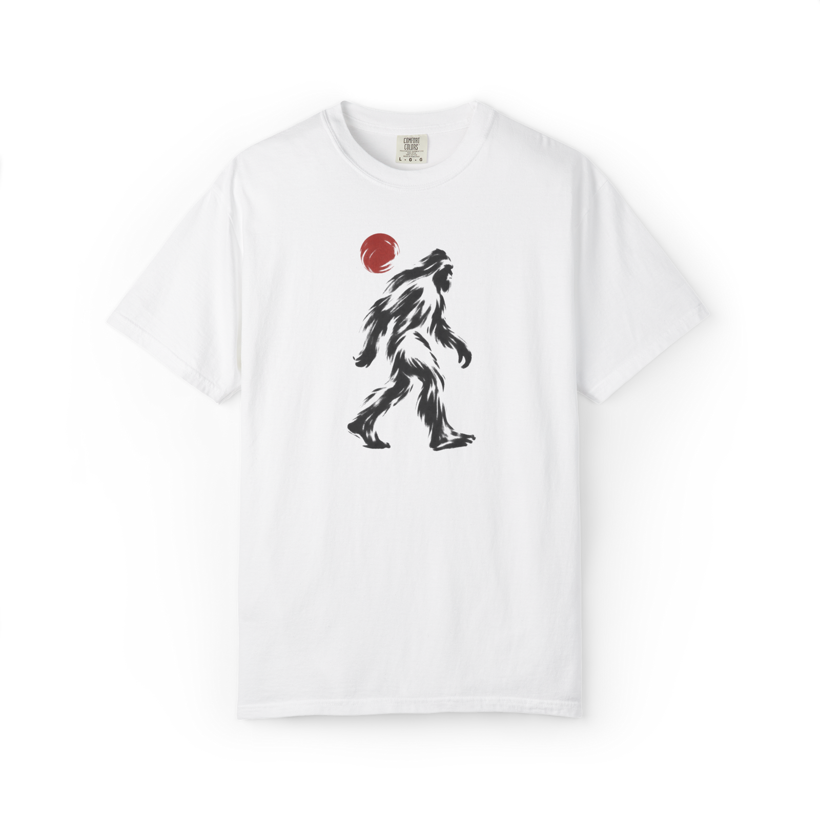 White Bigfoot t shirt featuring a black brush-style walking Sasquatch graphic with a red sun above the creature